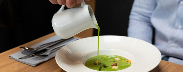 Ein Kellner schenkt im Restaurant bei Villach einem Gast die Suppe ein